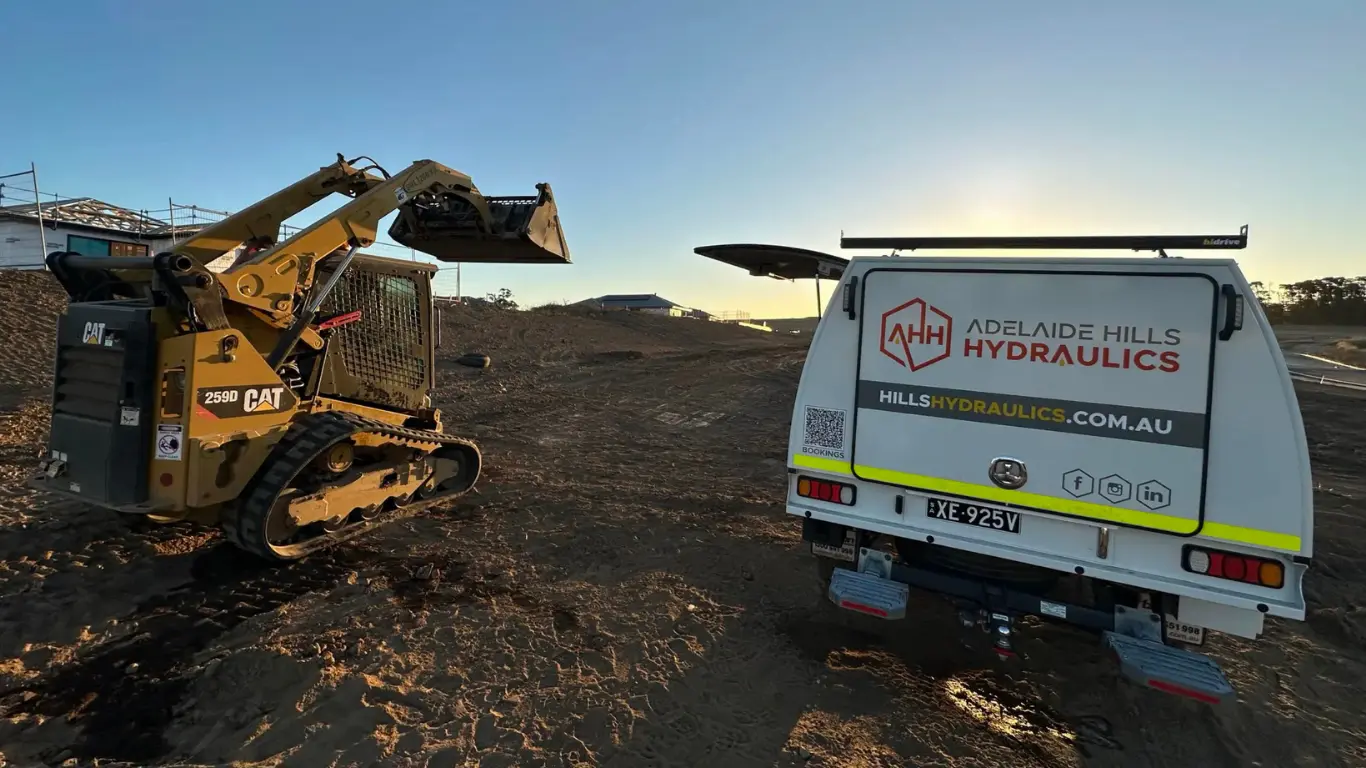 AHH service vehicle on site alongside a CAT loader at sunset